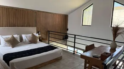 a bedroom with a bed and a desk and a balcony at Ambara Villa - Quiet Luxury in Umalas in Canggu