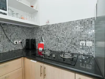 a kitchen with a black counter and a tile wall at The White House Villa Taeyvela Seminyak in Seminyak