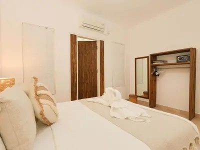 a bedroom with a bed with white sheets and a mirror at The White House Villa Taeyvela Seminyak in Seminyak
