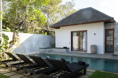 a villa with a swimming pool and lounge chairs at Villa Under the Sun - Seminyak in Seminyak