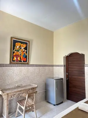 a kitchen with a table and a refrigerator in a room at OSA Guest House in Seminyak