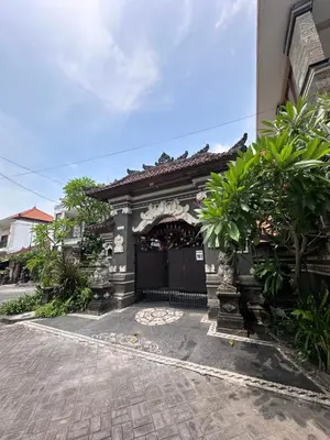a gate to a building with trees and a building at OSA Guest House in Seminyak