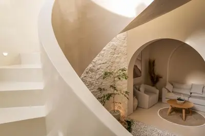 a spiral staircase leads to a living room with white furniture at Brand New Exquisite Luxury 5 BR Villa Umalas in Kerobokan