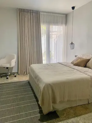 a bedroom with a bed and a chair and a window at Zen Home in Jimbaran