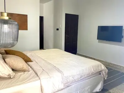 a bedroom with a bed with a tv on the wall at Zen Home in Jimbaran