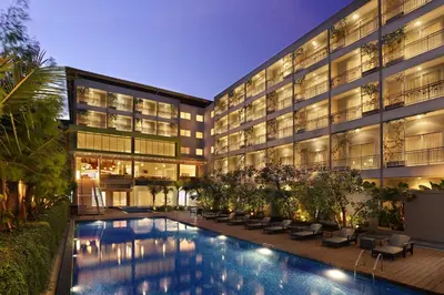 a hotel with a swimming pool in front of a building at Diamond Hotel Kuta Bali in Kuta