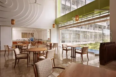 a restaurant with tables and chairs and a large window at Diamond Hotel Kuta Bali in Kuta