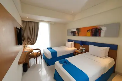 a hotel room with two beds and a desk at Zia Hotel Kuta in Kuta