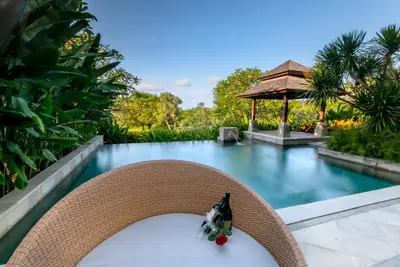 a wicker chair with a bouquet of flowers on it next to a pool at Luxury Apartment at AYANA Residences in Jimbaran