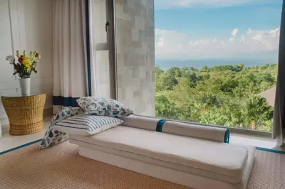 a couch in a room with a large window at Luxury Apartment at AYANA Residences in Jimbaran