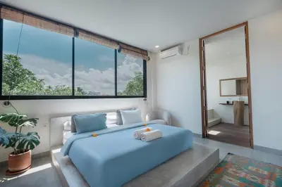a bedroom with a blue bed and large windows at Villa Kanan Seminyak - Stylish 2BR Villa Private Pool in Seminyak