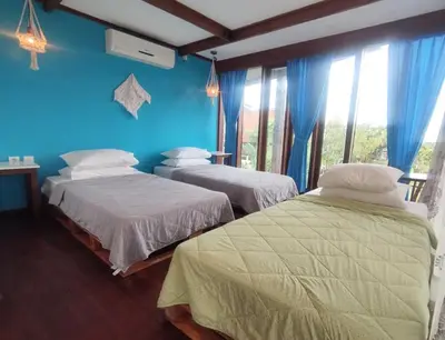two beds in a room with blue walls and windows at Bashania in Kerobokan