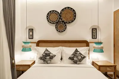 a bedroom with a bed with two tables and two clocks on the wall at Ben's Villa 1 by Alfred in Bali in Kerobokan