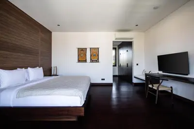 a bedroom with a bed and a desk and a television at Villa Gendang in Seminyak