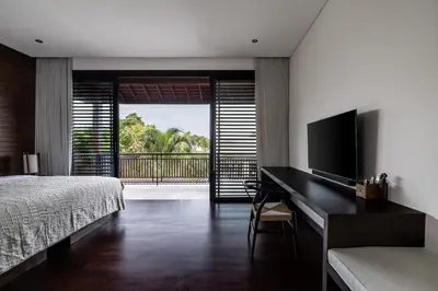 a bedroom with a bed and a desk with a television at Villa Gendang in Seminyak