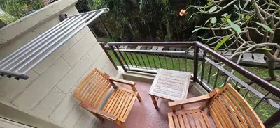 two wooden benches and a table on a balcony at The Palmana Tropical Courtyard Jayakarta Residence 12 in Seminyak
