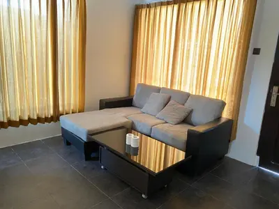 a couch in a living room with a table at Kubu Jimbaran in Jimbaran