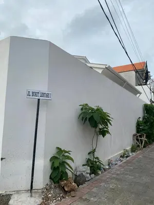 a street sign on the side of a white building at Kubu Jimbaran in Jimbaran