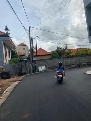 a person riding a motorcycle down a street at Kubu Jimbaran in Jimbaran