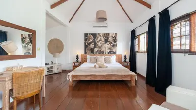 a bedroom with a bed and a table and chairs at Villa Mogi by Villa Finder in Seminyak