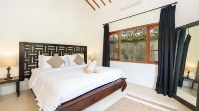 a bedroom with a large bed and a window at Villa Mogi by Villa Finder in Seminyak