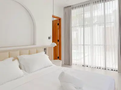 a bedroom with a large white bed and a large window at Burgundy - Twin Villa in Berawa Canggu in Canggu