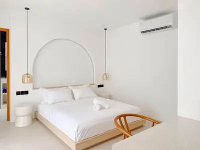 a white bedroom with a bed and a table at Burgundy - Twin Villa in Berawa Canggu in Canggu