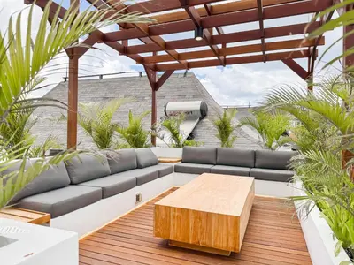 a patio with a couch and a wooden table at Burgundy - Twin Villa in Berawa Canggu in Canggu
