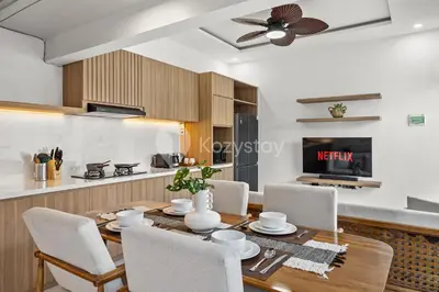 a dining room and kitchen with a wooden table and chairs at Navaya Villa by Kozystay - Seminyak in Seminyak