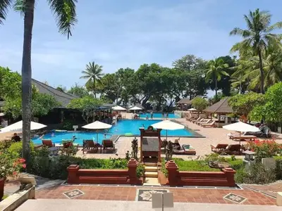 a pool with chairs and umbrellas in a resort at The Palmana Tropical Garden Jayakarta Residence 38 in Seminyak