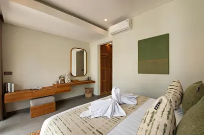a bedroom with a bed and a desk and a mirror at Levan Villa Seminyak in Seminyak