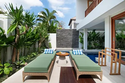 a patio with two chaise lounge chairs and a table at Levan Villa Seminyak in Seminyak