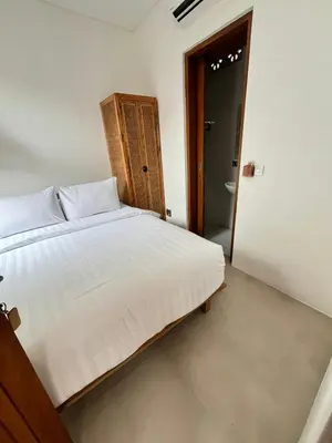 a bedroom with a large bed and a bathroom at Phil's Harmony Seminyak in Kerobokan
