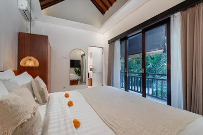 a bedroom with a large bed and a large window at Villa Kunti in Seminyak