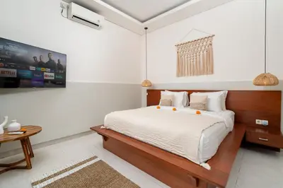a white bedroom with a bed and a table at Villa Kunti in Seminyak