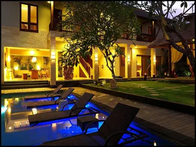 a resort with a pool with chairs and a house at The Secret Villas in Seminyak