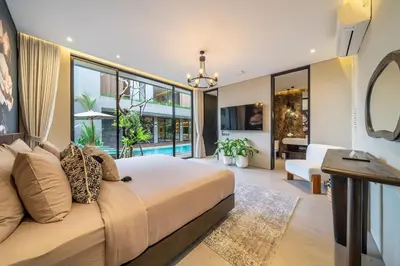 a bedroom with a large bed and a living room at The Plaza 4BR With Pool in Bali s Eat Street in Seminyak