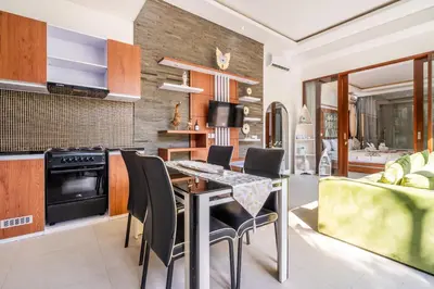 a kitchen and living room with a table and chairs at Villa Yudhistira by JB Villas in Seminyak