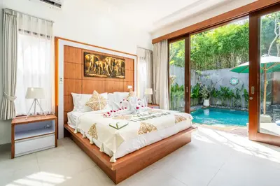 a bedroom with a bed and a swimming pool at Villa Yudhistira by JB Villas in Seminyak