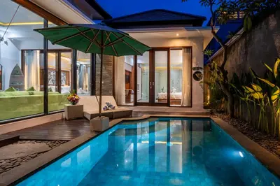 a swimming pool with an umbrella in a house at Villa Yudhistira by JB Villas in Seminyak