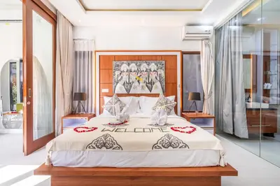 a bedroom with a large bed and glass walls at Villa Yudhistira by JB Villas in Seminyak