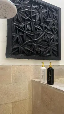 two bottles of soap sitting on a ledge in front of a painting at New Villa Soul asa in Seminyak