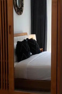 a bedroom with a bed with black pillows on it at NEW! Queen Villa - 2BR Villa in Seminyak in Seminyak
