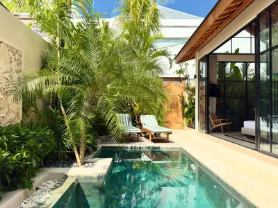 a swimming pool with a palm tree and a house at Villa Allany - Modern 2BR Tropical Hideaway Private Pool in Seminyak