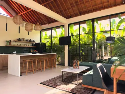 a living room with a green couch and a bar at Villa Allany - Modern 2BR Tropical Hideaway Private Pool in Seminyak