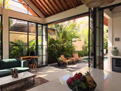 a living room with glass doors and a table at Villa Allany - Modern 2BR Tropical Hideaway Private Pool in Seminyak