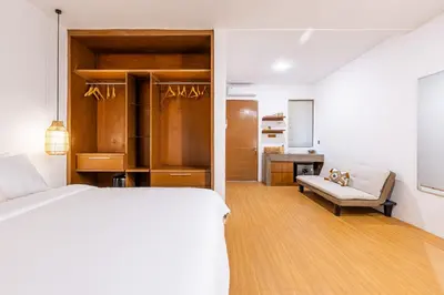 a white bedroom with a bed and a couch at SNUG Kuta in Kuta