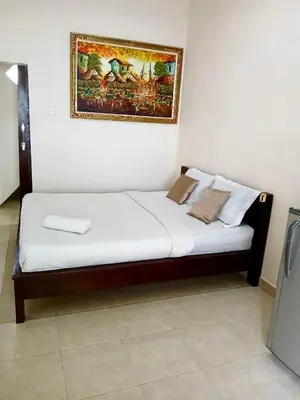 a bed in a room with a painting on the wall at OSA Guest House 3 in Seminyak