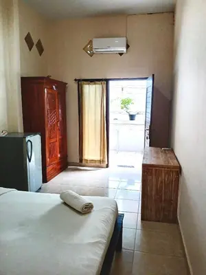 a room with a bed and a kitchen with a refrigerator at OSA Guest House 3 in Seminyak