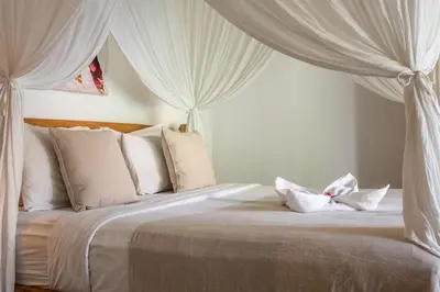 a bedroom with a white bed with white curtains at Renovated Villa Zayya, Central Oberoi Seminyak in Seminyak